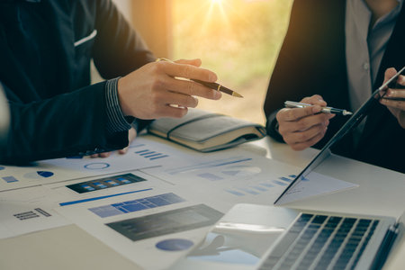 A group of business people are meeting to analyze data for a marketing plan. Office workers work in a team meeting with project planning documents on the conference table. Close-upの写真素材