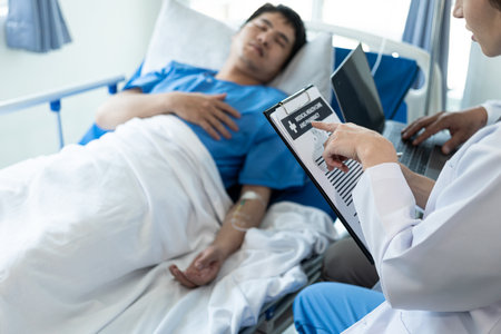 An Asian male patient lies in a hospital bed and is carefully looked after by a doctor. Doctor giving advice to male patient Working on health disease diagnosisの写真素材
