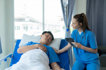 An Asian male patient lies in a hospital bed and is carefully looked after by a doctor. Doctor giving advice to male patient Working on health disease diagnosisの写真素材