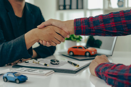 Man buys car and shakes hands with business salesman, closing car sales agreement, gesture and concept of giving keys to new owner and shaking hands at car show Close-up picturesの写真素材
