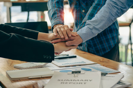 Businessmen working together in modern office Close up top view of businessmen holding hands together Group of hands, concept of unity and teamwork, celebrating success.の写真素材
