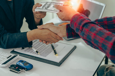 Man buys car and shakes hands with business salesman, closing car sales agreement, gesture and concept of giving keys to new owner and shaking hands at car show Close-up picturesの写真素材