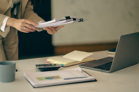 Accountant using calculator with laptop computer, budget and loan documents, Asian businesswoman meeting online to discuss project plans and financial results in office, close-up sの写真素材