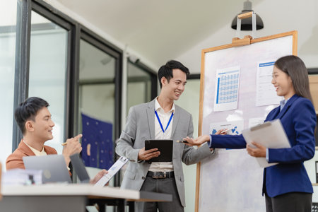 Team of successful Asian businessmen in suits working in conference room to discuss brainstorming, computation, analysis together on company growth goals and gross profit margins.の写真素材