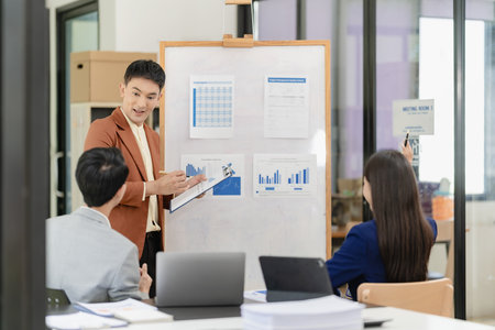 Team of successful Asian businessmen in suits working in conference room to discuss brainstorming, computation, analysis together on company growth goals and gross profit margins.の写真素材