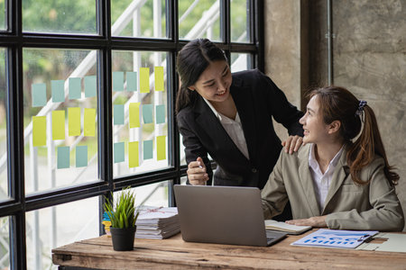 Two Asian female accountants have team meeting to summarize financial information in business office, creative female executive using tablet PC and smilingの写真素材