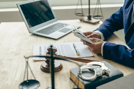 Lawyer holding money and justice concept Legal advisor holds a dollar bill with a hammer and the goddess of injustice on the table. Concept of corruption and embezzlementの写真素材