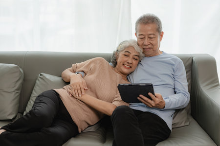 Asian senior couple looking at camera and smiling, senior smiling and looking at tablet Retired...