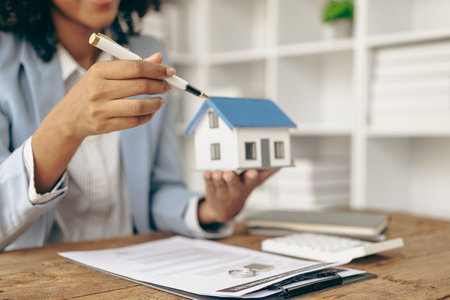 House model with real estate agent and client discussing home insurance contract Or the real estate loan history of the girl holding a small house model. Real Estate, Mortgages andの写真素材