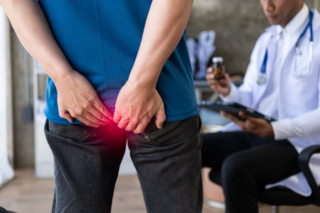 Man consulting doctor about hemorrhoids squeezes his butt treatment concept. Man touches her buttocks because of abdominal pain and hemorrhoids. health care conceptの写真素材