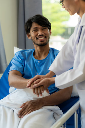 Male doctor talking with male patient in hospital bed Smiling doctor with clipboard caring for sick person, doctor delivering good news about diagnosis to middle-aged patient in hoの写真素材