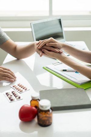 Young Asian doctor gives advice and delivers good news Discussing results or symptoms with a male patient sitting at a table in the clinic.の写真素材