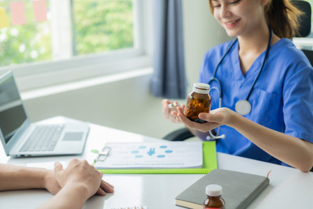 Young Asian doctor gives advice and delivers good news Discussing results or symptoms with a male patient sitting at a table in the clinic.の写真素材