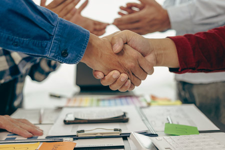 Young business people shaking hands and meeting with documents above to hire a partner or work together at the office, teamwork or researching a new marketing project in close-up.の写真素材