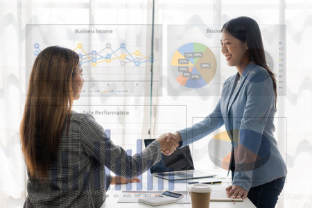 Two Asian businesswomen shake hands and congratulate each other on business success in joint financial business and investment in the company.の写真素材