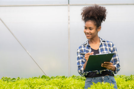 Portrait of young african american woman with clipboard in hydroponic greenhouseの写真素材