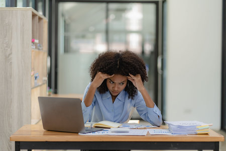 worried african american businesswoman working with laptop in officeの写真素材