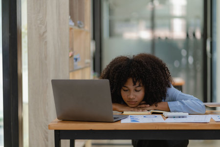 Young african american businesswoman sleeping at her desk in officeの写真素材