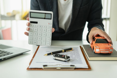 Businessman working with calculator and car model on desk. Concept of car insuranceの写真素材