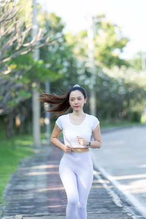 Woman stretching her legs after running or jogging in a city park. For good health, warm up before going for a refreshing run in the nature park. Asian runner after exerciseの写真素材