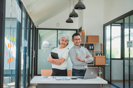 Senior Asian business woman and young man working together analyzing finances senior staff teach marketing and planning to younger staff woman holding graph and chart with a happyの写真素材