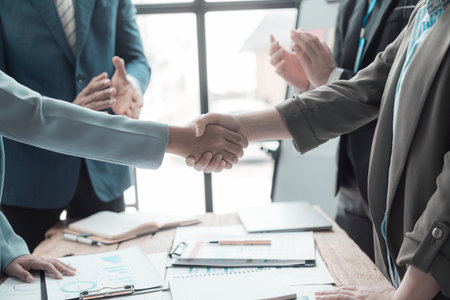 Businessmen holding hands having documents with graphs and financial charts, concept of business agreement together, close-up image.の写真素材