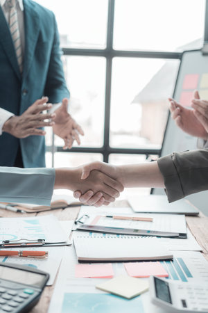 Businessmen holding hands having documents with graphs and financial charts, concept of business agreement together, close-up image.の写真素材