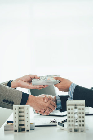 A condo sales representative shakes hands with a client to come to an agreement on the real estate sales title while touring the property in the office.の写真素材
