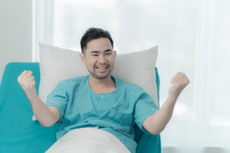 A seriously ill man lies alone in a hospital bed. The patient is recovering after successful surgery. Sick male patient lying on bed in private ward in hospitalの写真素材