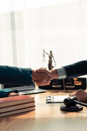 Handshaking with client, lawyer making documents, contract, agreement, cooperation agreement with client at lawyer's table with scales and a hammer on the table Close-up photoの写真素材