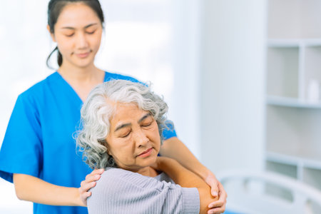 Young Asian doctor in uniform gives medical advice to senior female patient in hospital wardの写真素材