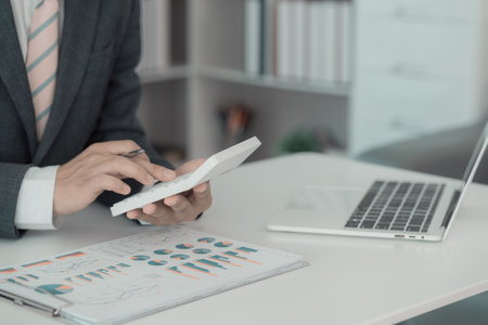 Accountant analyzing investment chart, invoice and pressing calculator button over document,...