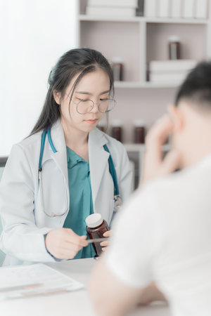Young Asian man explains symptoms to psychologist while female doctor takes notes at clinic.の写真素材
