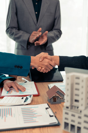 Handshake and conclusion of agreement between real estate agent, seller and new owner. Sale, purchase, loan, finance, insurance, house rental agreement. Vertical close-up photoの写真素材