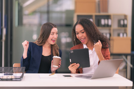 Two business women smile and raise their hands. feel happy The work is finished. Teamwork succeeds, victory with laptop computer concept of successの写真素材