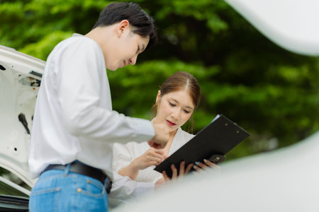 Complaint officer inspecting damaged car on the side of the road, demonstrating trust and confidence. Customer satisfaction with service delivery and customer satisfaction.の写真素材
