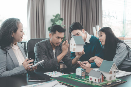 Business team signing investment agreement for residential real estate. Group of professionals in suits meeting in office with financial agreement documents on table.の写真素材