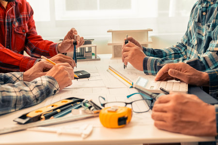 Teams of engineers and builders are looking at floor plans together on laptops. Architects meet at work to plan new blueprints. They work hard for small businesses in apartment buiの写真素材