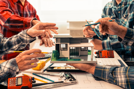 Teams of engineers and builders are looking at floor plans together on laptops. Architects meet at work to plan new blueprints. They work hard for small businesses in apartment buiの写真素材