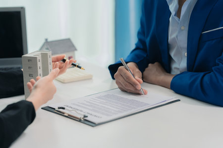 Real estate agent with documents to buy new house of house plan and keys on table. At table with model house. Real estate. Close up.の写真素材