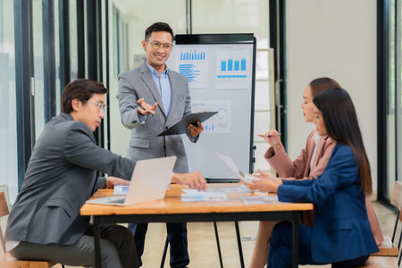 Group of Asian business people discussing charts and graphs showing the results of successful...