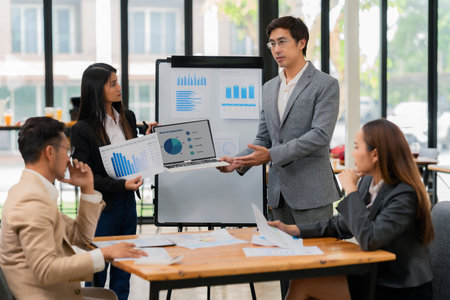 Group of Asian business people discussing charts and graphs showing the results of successful business investment and growth showing the results of successful teamwork.の写真素材