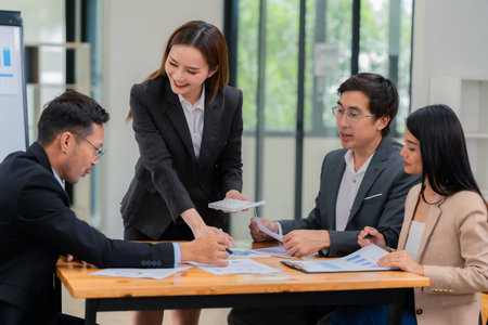 Group of Asian business people discussing charts and graphs showing the results of successful business investment and growth showing the results of successful teamwork.の写真素材