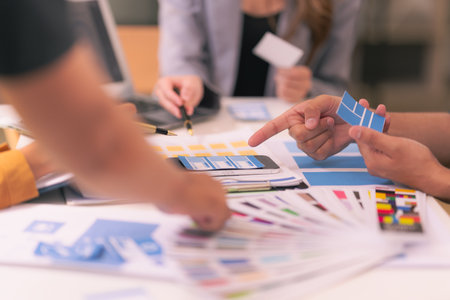 A design team focused on analyzing interface layouts and brainstorming to improve the user experience in a mobile responsive workshop with UI/UX Front End Designer Previewing.の写真素材