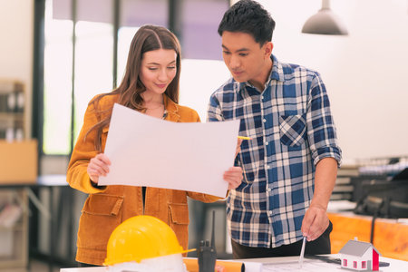 A team of industrial engineers are meeting to analyze machinery plans and discuss projects at the table.の写真素材
