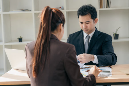 Two Asian businessmen discussing charts and graphs showing the results of successful teamwork. Using...