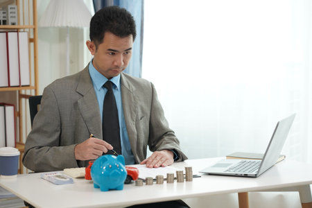 Businessman is placing coins next to toy car, which represents saving money to buy a car. Finance concept, planning future.の写真素材