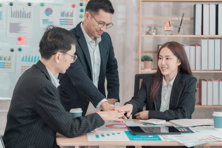 Business team discussing charts and graphs about investment and business growth. Business colleagues analyzing financial data at desk in office.の写真素材