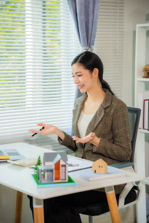 Young Asian woman working as a customer service representative on the phone in an office with a microphone and headset in a customer contact center office. Vertical photo.の写真素材