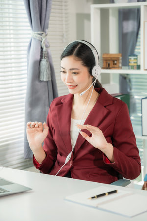Young Asian woman working as a customer service representative on the phone in an office with a microphone and headset in a customer contact center office. Vertical photo.の写真素材